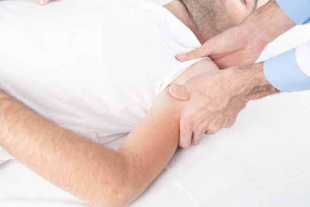 白种人医生按摩病人的肩膀。图片下载