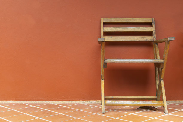 赤陶地板上摆放着木椅，背景是橙色的灰泥墙，阳台上摆放着木椅。图片下载