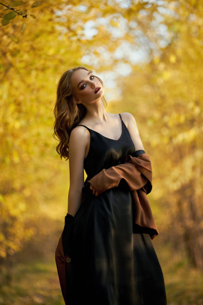 一个美丽的时尚女人的肖像在黄色的秋天的树的背景图片下载