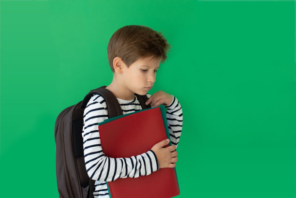 一个无聊的男生，脸上满是空白。带着书包和课本的小学生。回到学校图片下载