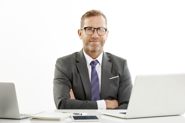 双臂交叉坐在办公桌前的商人图片下载