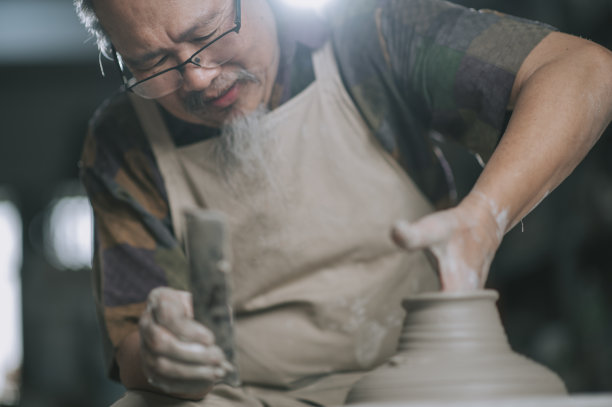 亚洲华人高级泥塑艺术家在他的工作室与纺织陶轮工作图片下载