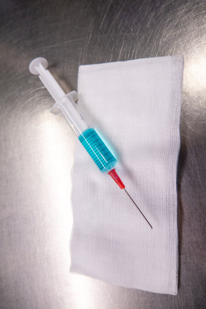 注射器装满蓝色液体躺在白色敷布上图片下载