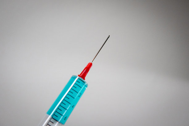 在白色背景下拿着装有蓝色液体的医疗注射器图片下载