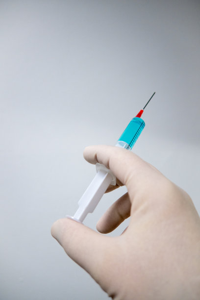 一只戴手套的手拿着一个装有蓝色液体的医疗注射器图片下载