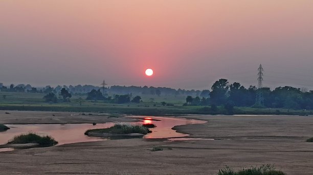 太阳落在山间的一条河上。图片下载