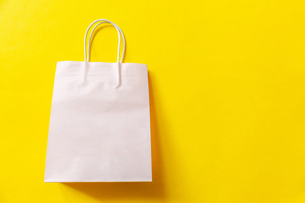 简单的最小设计购物袋孤立在黄色的背景。网上或购物中心购物狂概念。黑色星期五圣诞季大减价。平铺顶视图复制空间，模拟图片下载