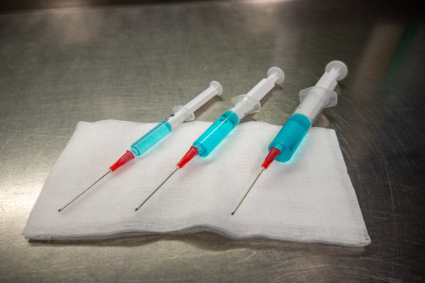 3个不同大小的注射器装满蓝色液体躺在白色敷布上图片下载