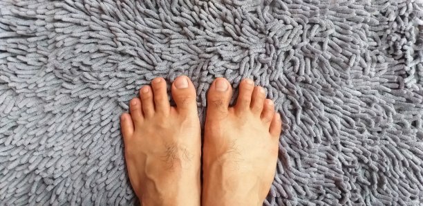 光着脚在地毯上。两只脚站着。灰色的地毯。毛茸茸的地毯。前视图。图片下载