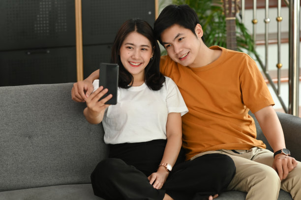 一对快乐的年轻夫妇在客厅的沙发上自拍。图片下载