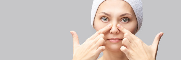 漂亮女人给自己做面部按摩。灰色背景。图片下载