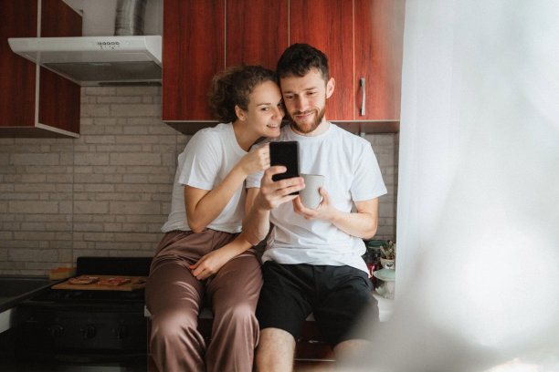 年轻漂亮的夫妇在厨房里喝茶或咖啡，然后自拍图片下载