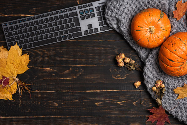 把笔记本电脑放在办公桌上，放上黄色和红色的枫叶和南瓜图片下载