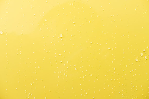 近距离拍摄的光滑的黄色汽车漆面。以水滴和光线为背景。背景或壁纸概念。图片下载