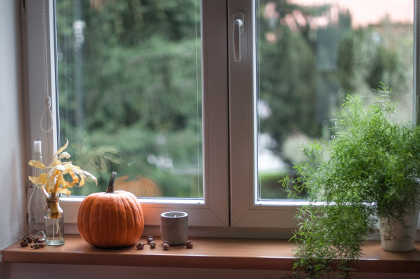 窗台上放着橙色的南瓜、秋叶、蜡烛和芦笋。图片下载