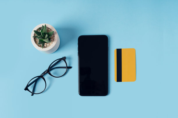 品牌模型。蓝色背景上有智能手机，信用卡，眼镜和花。平的。网上购物的概念。图片下载