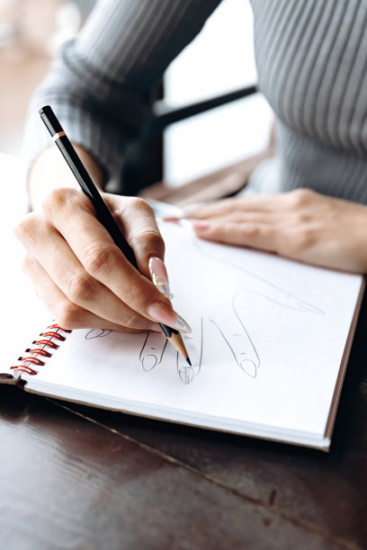 美甲师在一个特制的笔记本上画出指甲设计的草图。美甲师在一个特制的笔记本上画出指甲设计的草图。图片下载