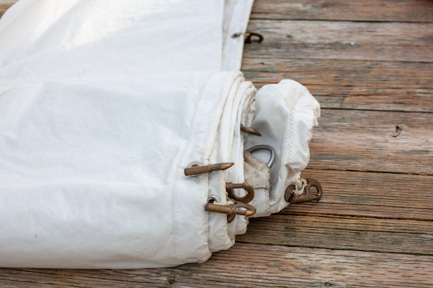 船坞上卷起了一张白色的三角帆，上面有栓绳和铜钩缝在船帆上。图片下载