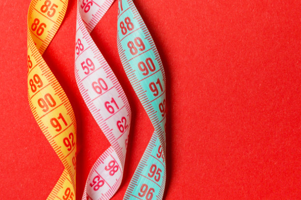 在红色背景上的螺旋彩色卷尺俯视图。完美女性形象的概念与空间为您的想法图片下载