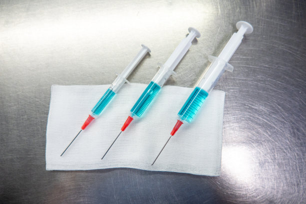 3个不同大小的注射器装满蓝色液体躺在白色敷布上图片下载