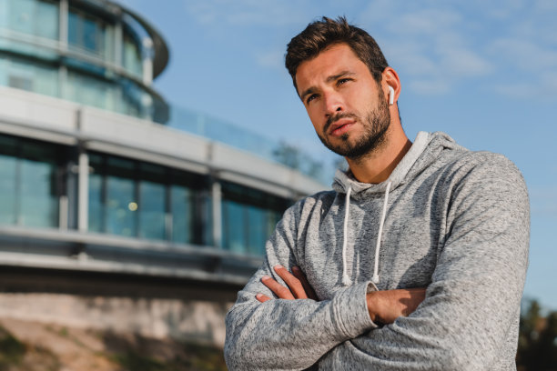 年轻英俊的男运动员在戴着耳机跑步后交叉双臂图片下载