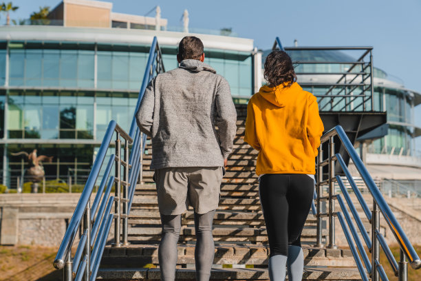 两名男女慢跑者穿着运动服在户外爬楼梯的背影照片图片下载