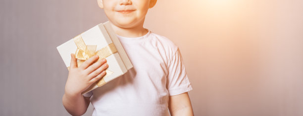 漂亮的小男孩穿着白色t恤，手里拿着礼物图片下载