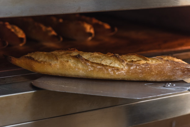 在面包店做手工面包。面包师和面包的特写，模糊的背景图片下载