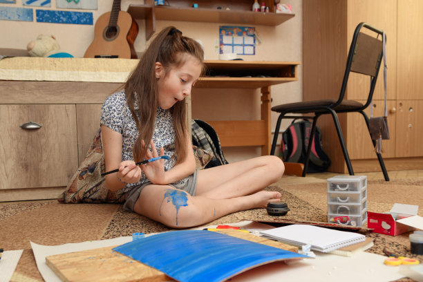 女孩在家里画画，进行艺术创作，用纸、颜料和画笔制作创造性的艺术品图片下载