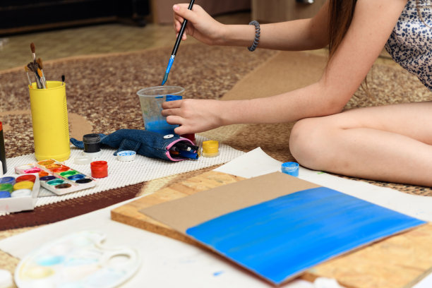 女孩在家里画画，进行艺术创作，用纸、颜料和画笔制作创造性的艺术品图片下载
