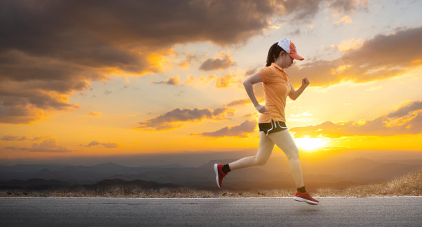 照片侧视图亚洲年轻女子在柏油路上奔跑，夕阳正落在山后的背景下图片下载