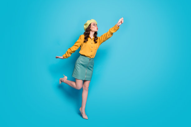 惊讶的女孩的全长照片牵手试着抓空气飞阳伞走穿好看的衣服鞋子孤立在蓝色背景图片下载