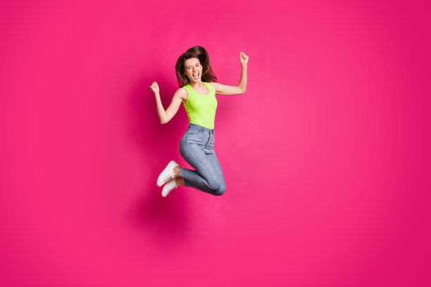 全身照片的兴奋，快乐的年轻女孩庆祝胜利，欢呼，是的，是的，跳拳头，手孤立在粉红色的背景图片下载