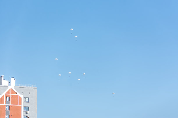 蓝天中白色的降落伞。一群伞兵在城市上空进行演习。图片下载