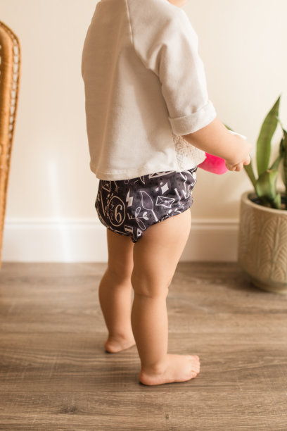 一个19个月大的蹒跚学步的小女孩，穿着灰色和白色的可重复使用布尿布和白色衬衫图片下载