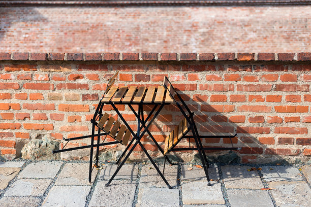 户外街头咖啡馆的桌子准备服务红砖墙。空的咖啡馆露台与木制桌子和椅子，早上的时间。图片下载