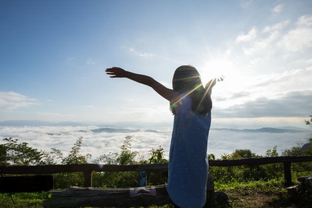 亚洲小女孩举起双臂，望着美丽的雾和山，享受着美丽的自然和清新和幸福图片下载