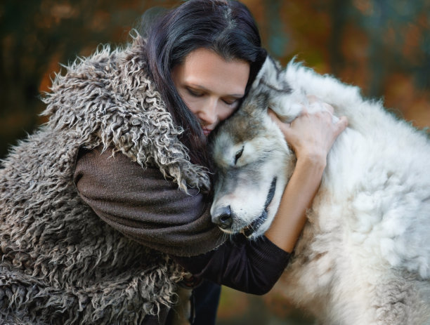 在秋天的森林里，一名妇女抱着她的狗图片下载