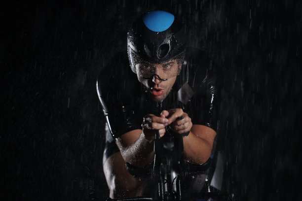 在雨夜中骑自行车的铁人三项运动员图片下载