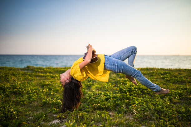 年轻女子在海边和尤克里里琴在空中飘浮图片下载