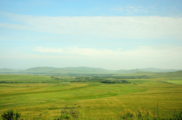 群山环绕着一望无际的草原和肥沃的牧场。图片下载