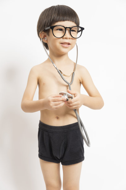 亚洲男孩微笑着，在白色背景上玩听诊器。图片下载