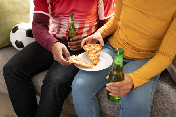 坐在家里的沙发上，喝着啤酒和披萨图片下载