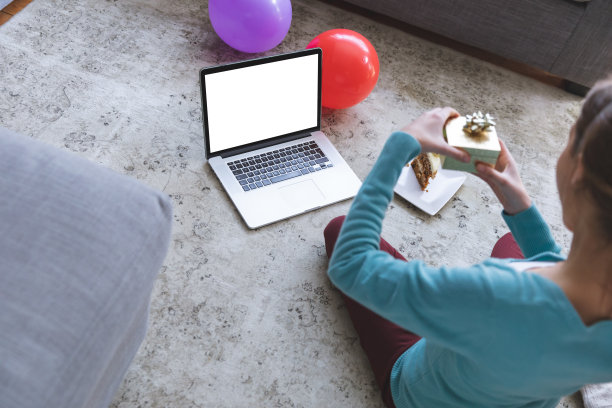 一个拿着一块蛋糕的女人正在用她的笔记本电脑进行视频通话图片下载