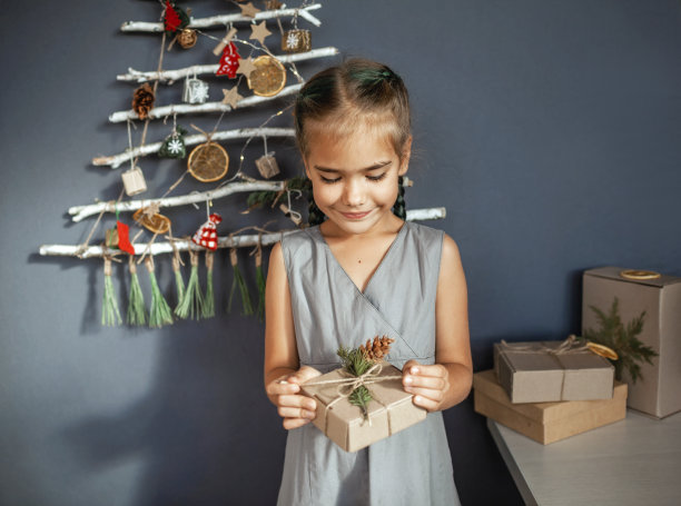 女孩靠近原来用树枝做成的圣诞树，生态玩具，零浪费节日图片下载