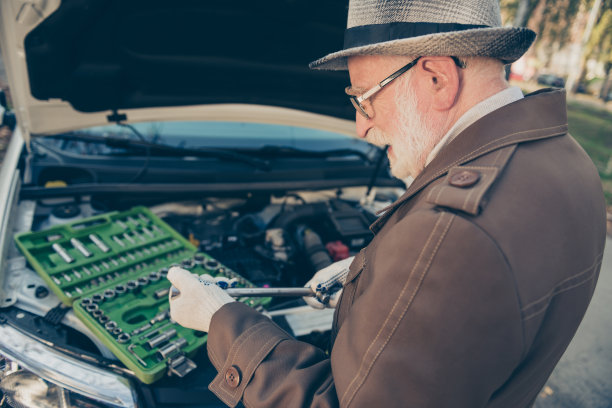 老人爷爷的照片，拿着器械箱打开车盖，穿着棕色夹克，戴着眼镜在户外图片下载