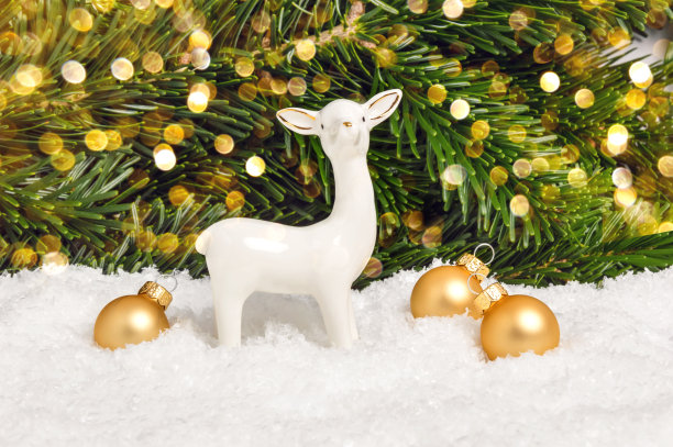 白色的圣诞驯鹿和金色的雪球与松树和散焦作为背景。节日贺卡。圣诞快乐，恭贺新禧图片下载