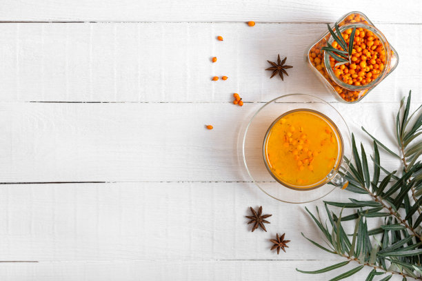 彩色热天然沙棘茶在一个玻璃杯，新鲜的生浆果和叶子，蜂蜜，茴香和肉桂棒。维生素保健药饮料。热饮的概念。俯视图，复制空间素材图片