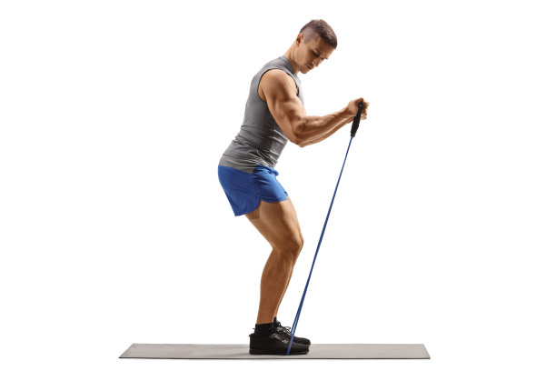 一个肌肉男在一个运动垫上用一个阻力带锻炼的全长侧面照片图片下载