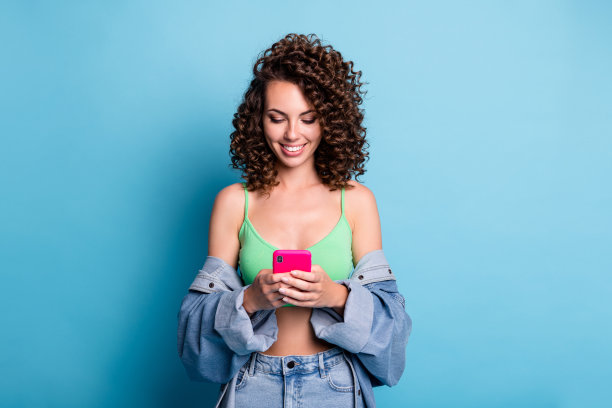积极的年轻女孩的照片博主用智能手机阅读社交媒体千禧新闻分享订阅转发穿好看的衣服孤立在蓝色柔和的颜色背景图片下载